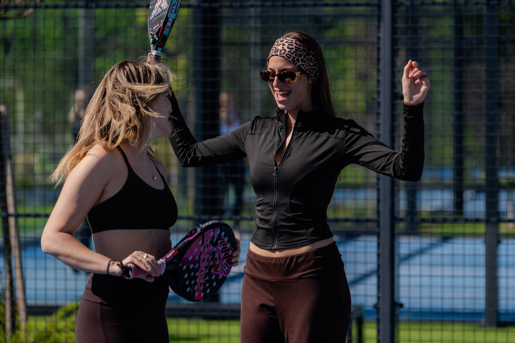 Two guests laughing together on the padel court